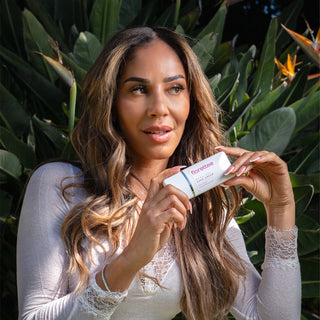 Model holding Florettee Rose Oil Hand Cream with fresh roses.