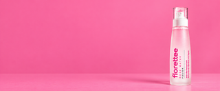 A bottle of Florettee Rose Water facial mist on a solid pink background, positioned on the right side with ample negative space on the left.
